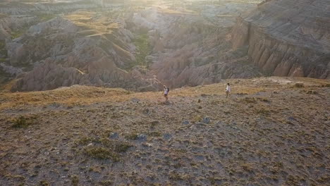 orbiting aerial with lens flare: hikers on hoodoos canyon rim trail