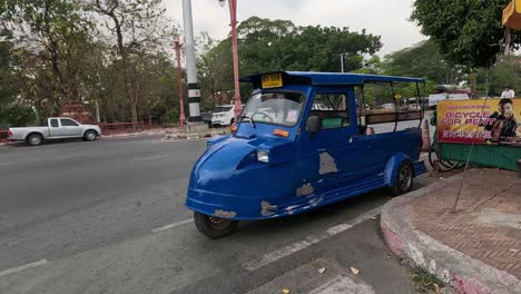 blue tuk-tuk turns at a crowded city junction