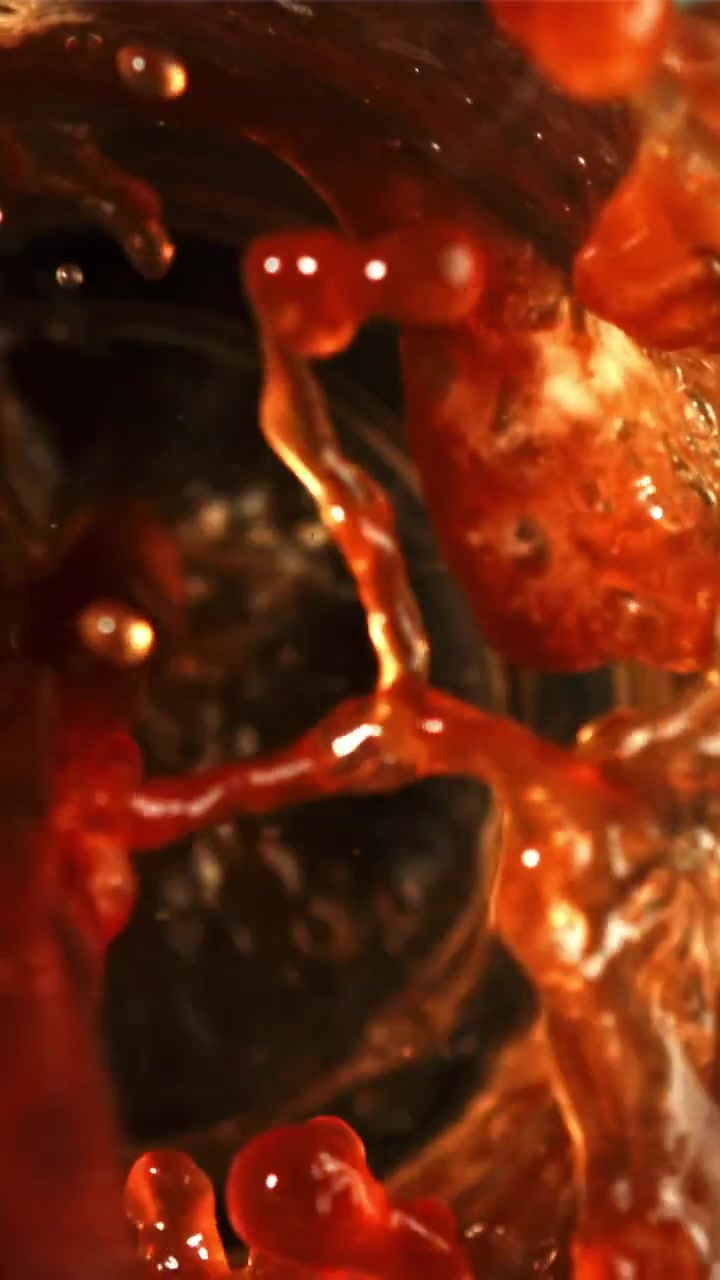 Primo piano al rallentatore di liquido rosso scuro che si versa e schizza