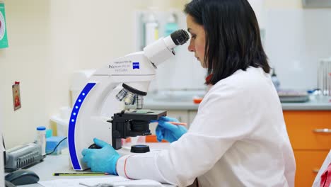 young woman researcher works with contemporary microscope. laboratory worker looking through the microscope. lab industry concept.