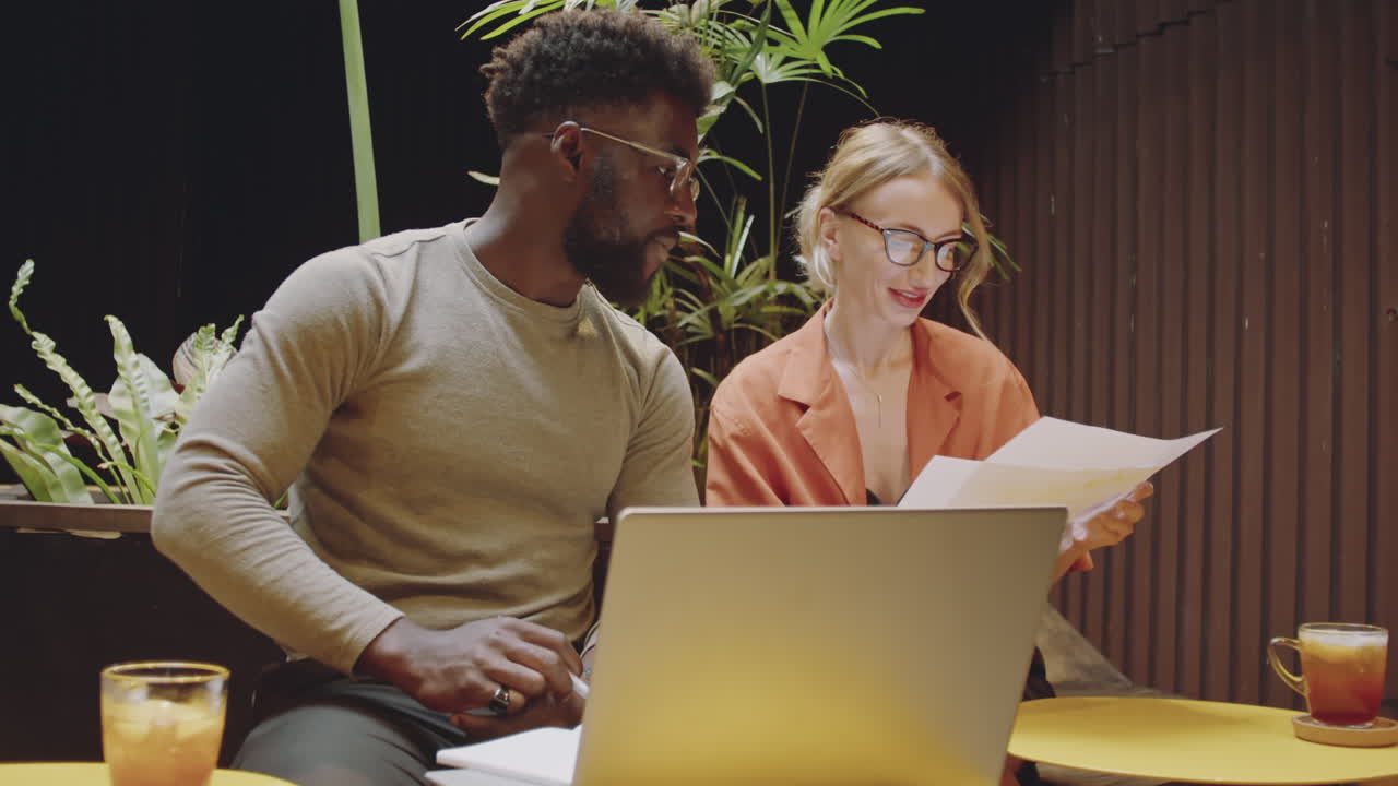 Coworkers Using Laptop and Discussing Papers in Cafe