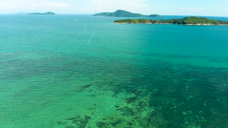 drone shot panning from left to right over rawai beachfront overlooking the small islands, boats, and the sandy beaches along the coastline of phuket in thailand