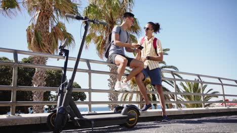 happy diverse gay male couple using smartphone at promenade by the sea, slow motion