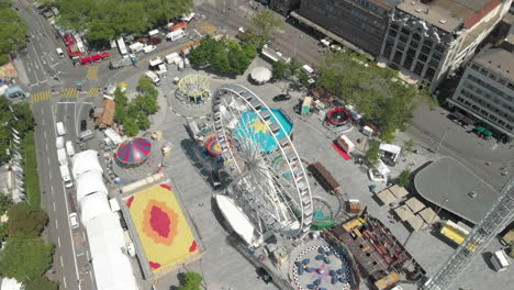 un dron aéreo en órbita voló hacia arriba y alrededor de la rueda de la fortuna del parque de diversiones con la ciudad de zúrich, suiza en el fondo durante el zürichfest