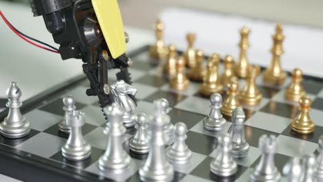 closeup yellow robot arm playing move chess on chessboard