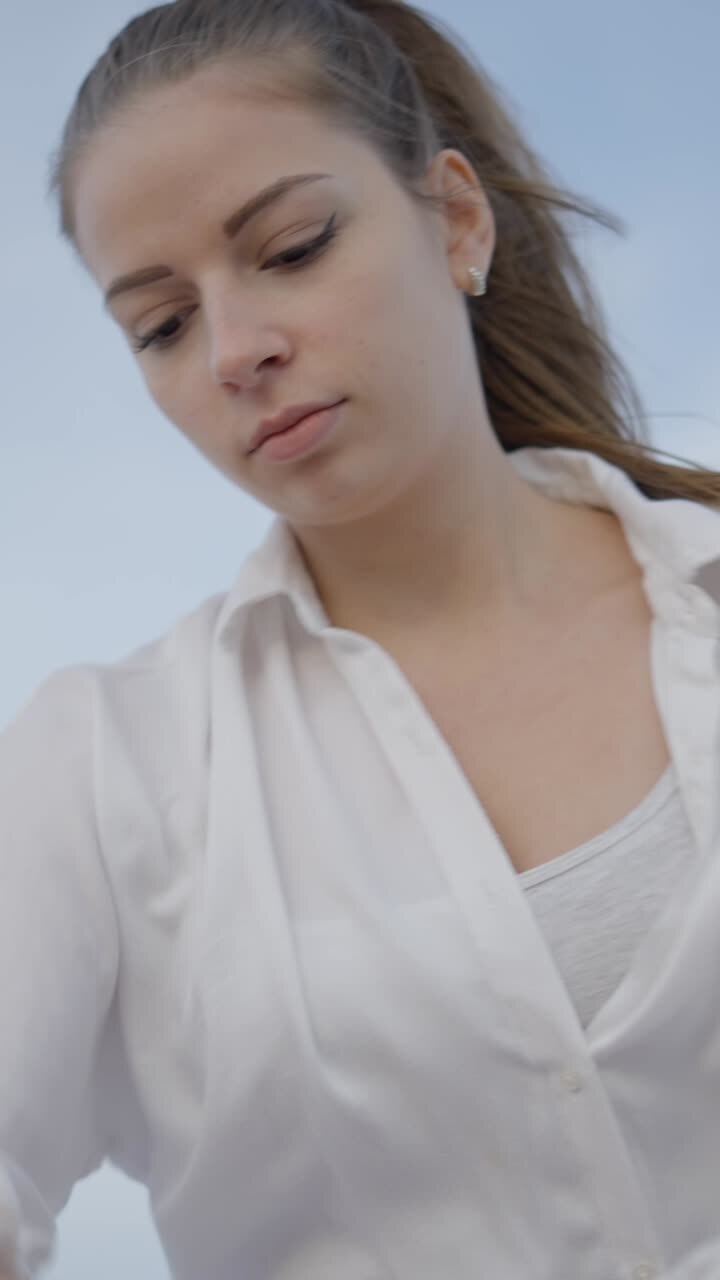 Close-up of a Young Woman in a White Shirt Looking Down