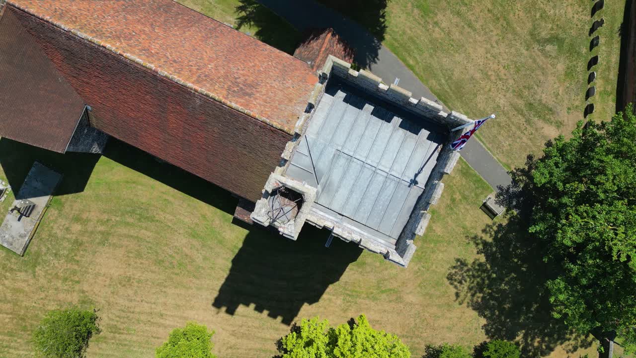 A top-down roll-shot of the tower of St Mary's church in Chartham, with a union flag flying from the top