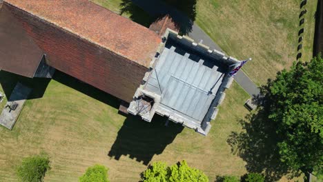 a top-down roll-shot of the tower of st mary's church in chartham, with a union flag flying from the top