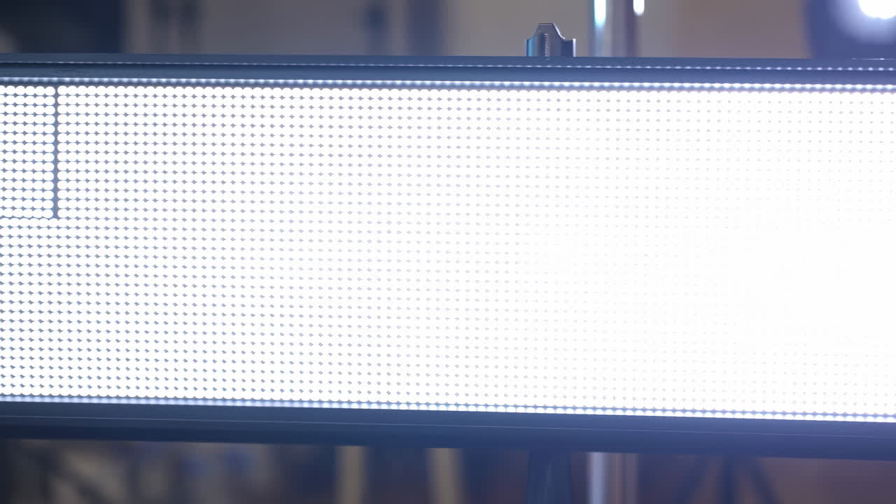 Primo piano di un pannello LED luminoso che mostra una griglia, con una superficie bianca sovraesposta che rivela una matrice di pixel e una fine perforazione.