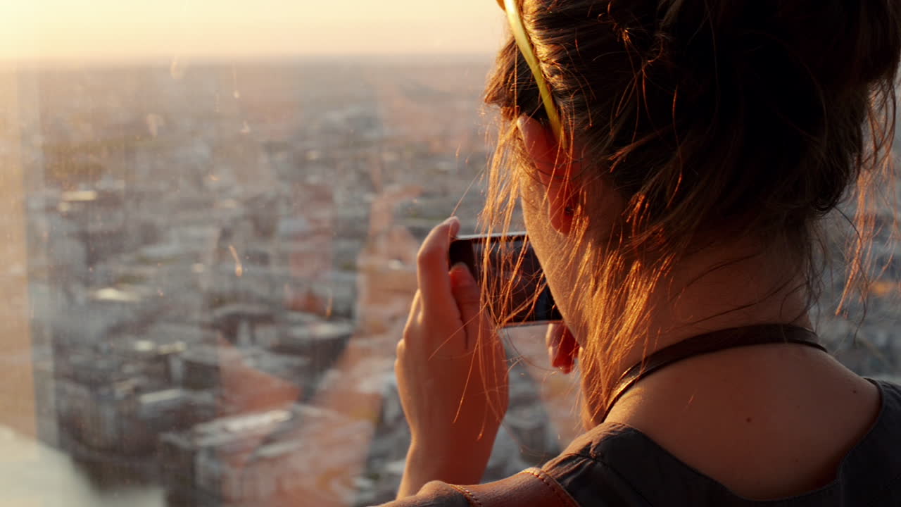 Turista che scatta una fotografia del tramonto nello skyline di Londra, vista da The Shard.