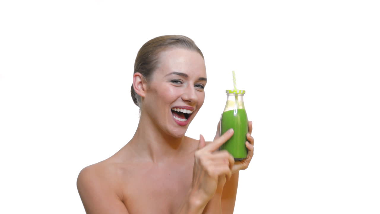mujer vegana en forma bebiendo jugo de vegetales verdes de una botella de vidrio con paja orgánica
