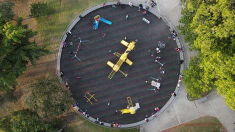 vista aérea de arriba hacia abajo de niños disfrutando de columpios y toboganes en el parque al aire libre