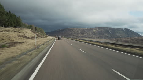 toma en movimiento de un vehículo que conduce por la carretera con otro tráfico con maravillosa luz de puesta de sol y nubes y montañas en edimburgo, escocia