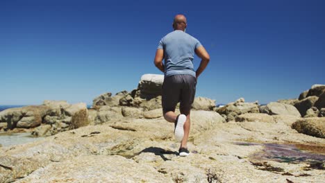 Senior-african-american-man-exercising-running-on-rocks-by-the-sea