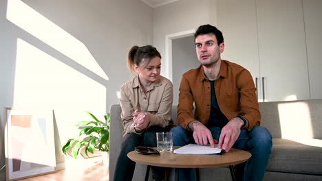 blind man reading a braille book aloud and his girlfriend listening him while sitting on sofa at home 1