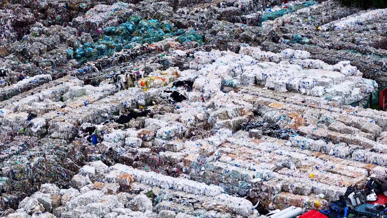 Aerial backdrop texture of compressed plastic waste bales stacked at recycling facility, drone