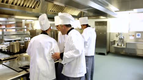 jefe de cocina supervisando a su equipo y luego sonriendo a la cámara