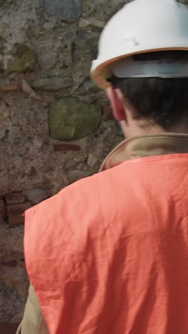 architect with helmet checking for the balance of an old wall