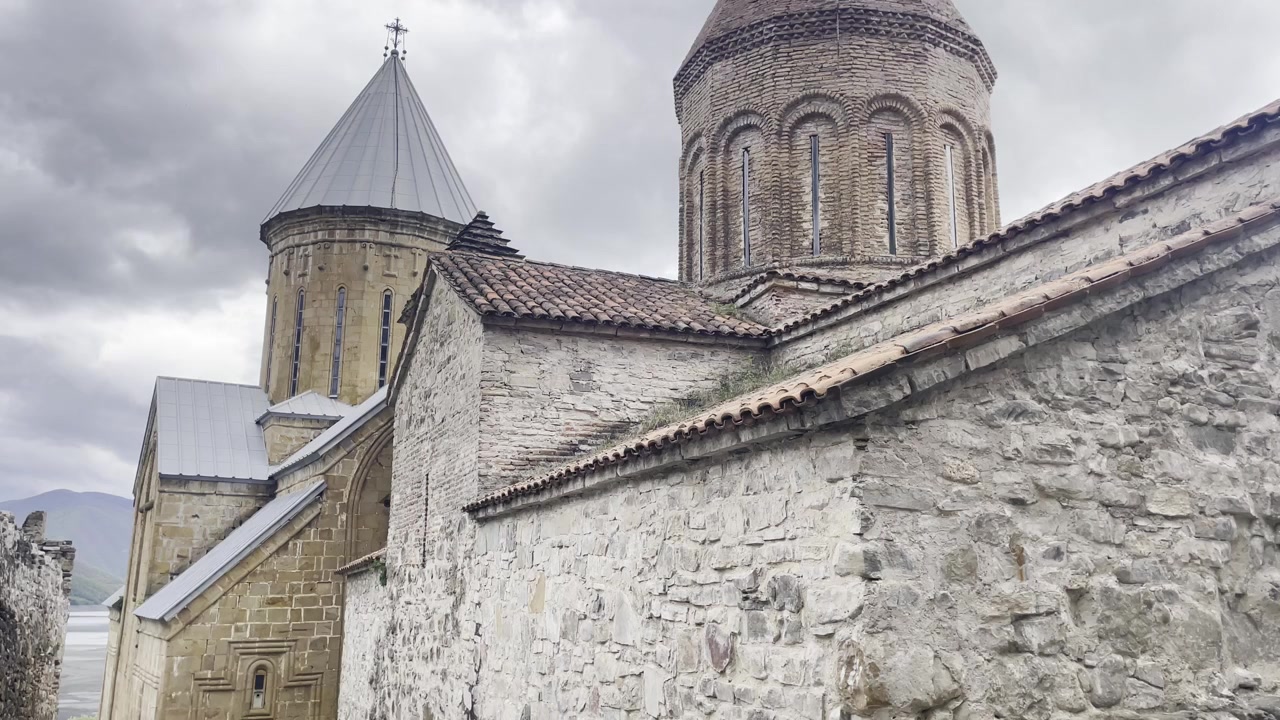 tilt up wide angle stone masonry and ancient walls of the Ananuri Fortress church, showcasing the intricate medieval architecture and traditional tiled roofs in the heart of Georgia