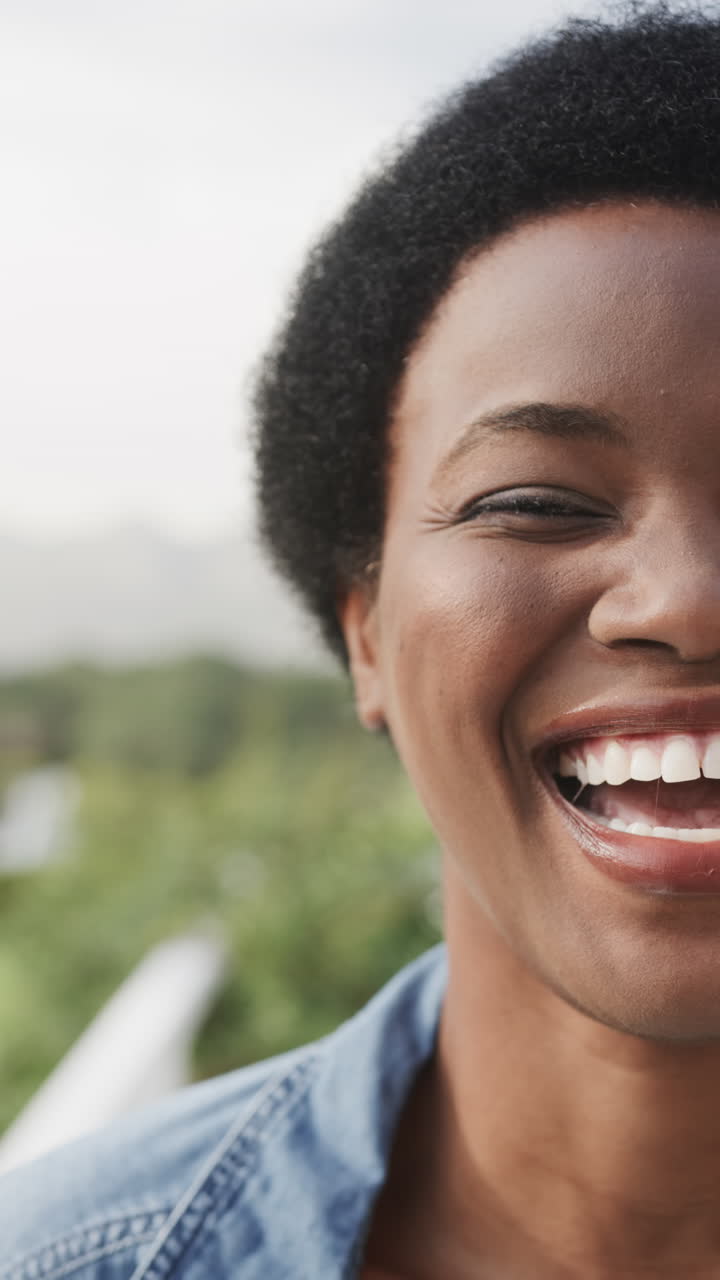 Vertical video of half portrait of happy african american woman on sunny terrace, slow motion