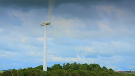 Windmill-spinning-and-clouds-racing-by-with-cloud-shadows-on-tree-line