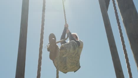 fit caucasian female soldier climbing a rope on an obstacle course