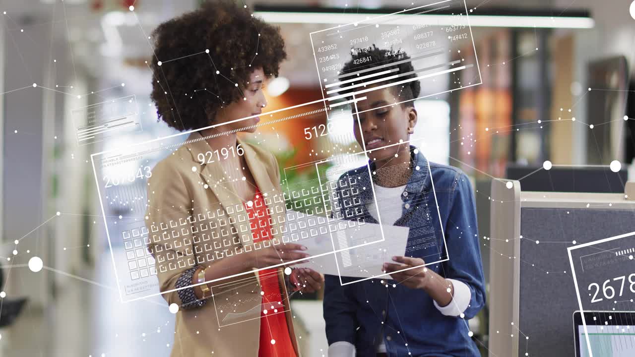 Standing pair in business casual reviewing papers in open office with laptop and AR overlays