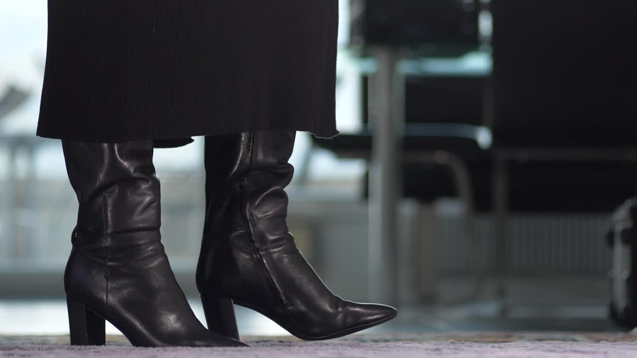 una mujer de negocios nerviosa con un vestido usa botas negras brillantes, entra en la imagen, hace zoom