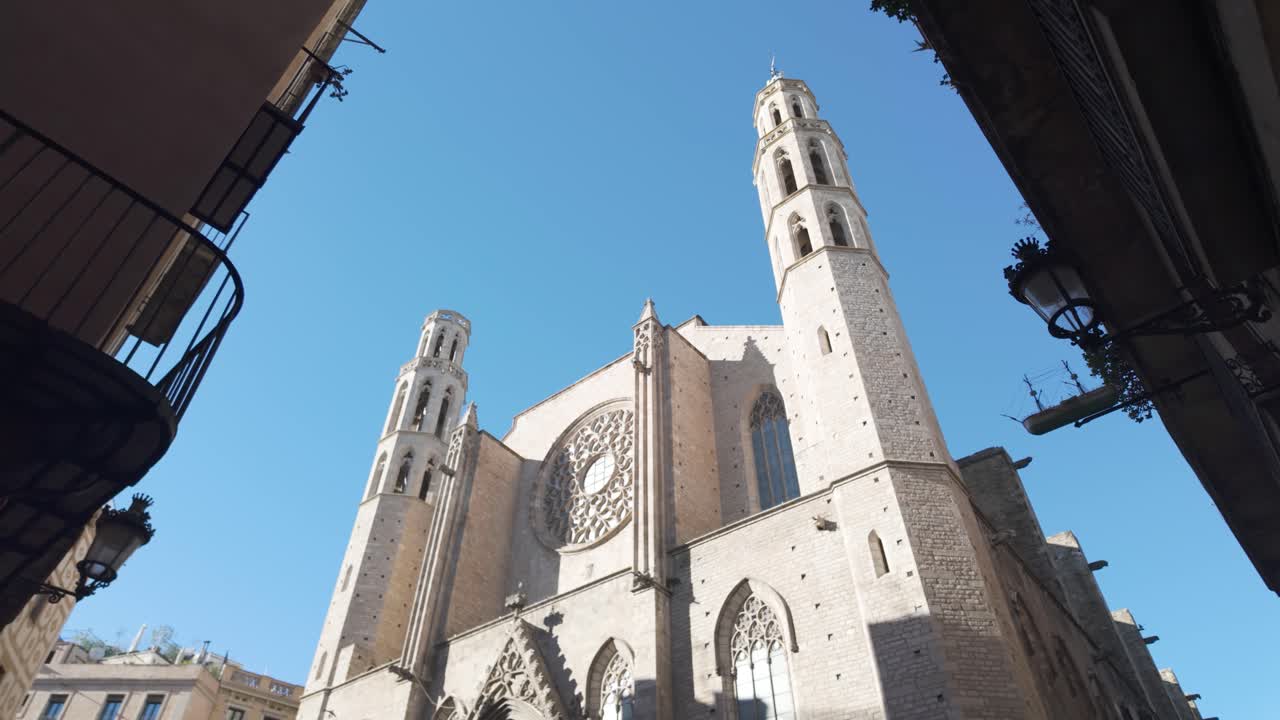 la arquitectura gótica de santa maría del mar en barcelona brilla bajo un cielo azul brillante, mostrando su intrincada fachada y figuras icónicas.