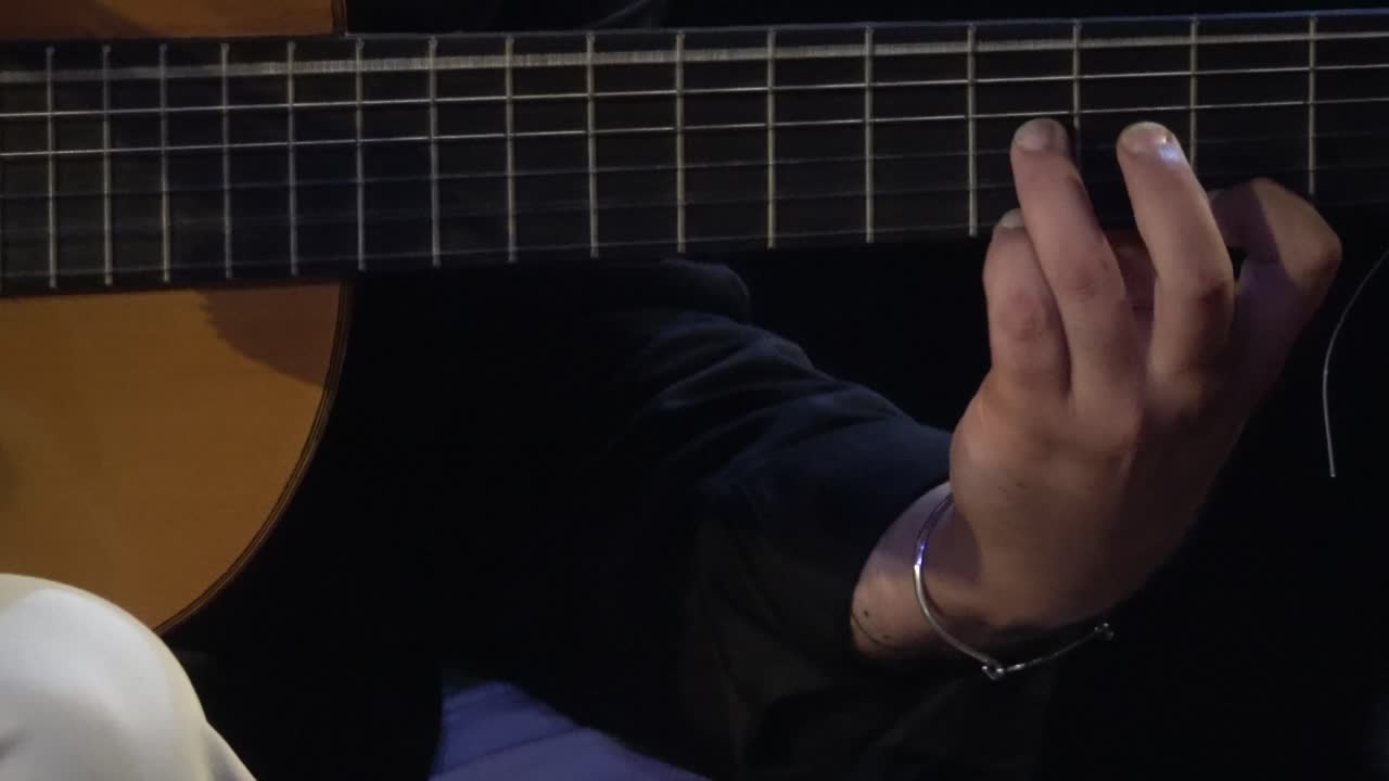 暗い部屋で伝統的なギターを演奏するフラメンコミュージシャン