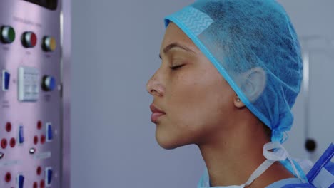 Close-up-of-African-American-female-doctor-looking-at-x-ray-report-on-light-box-in-hospital