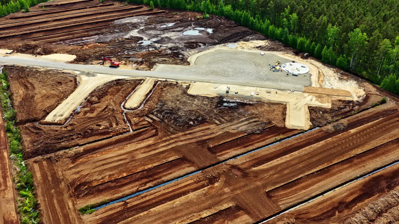 Large peat field and wind turbine foundation under construction in forest area