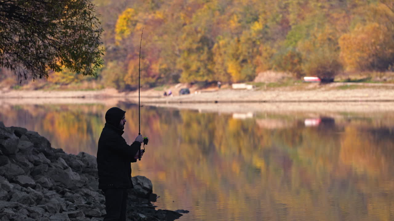 A fisherman fishing on a lake in autumn