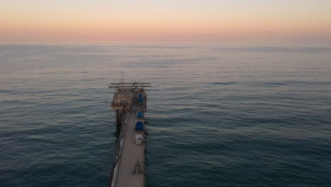 Scripps-Pier-Vertical-Elevation-Over-Deep-Blue-Ocean-With-Colorful-Sky-In-Background-At-La-Jolla,-San-Diego,-California