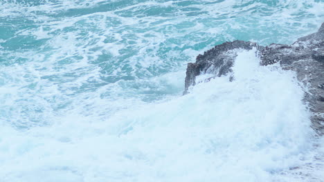 Big-sea-waves-crushing-on-rocky-shore-creating-foam---close-up