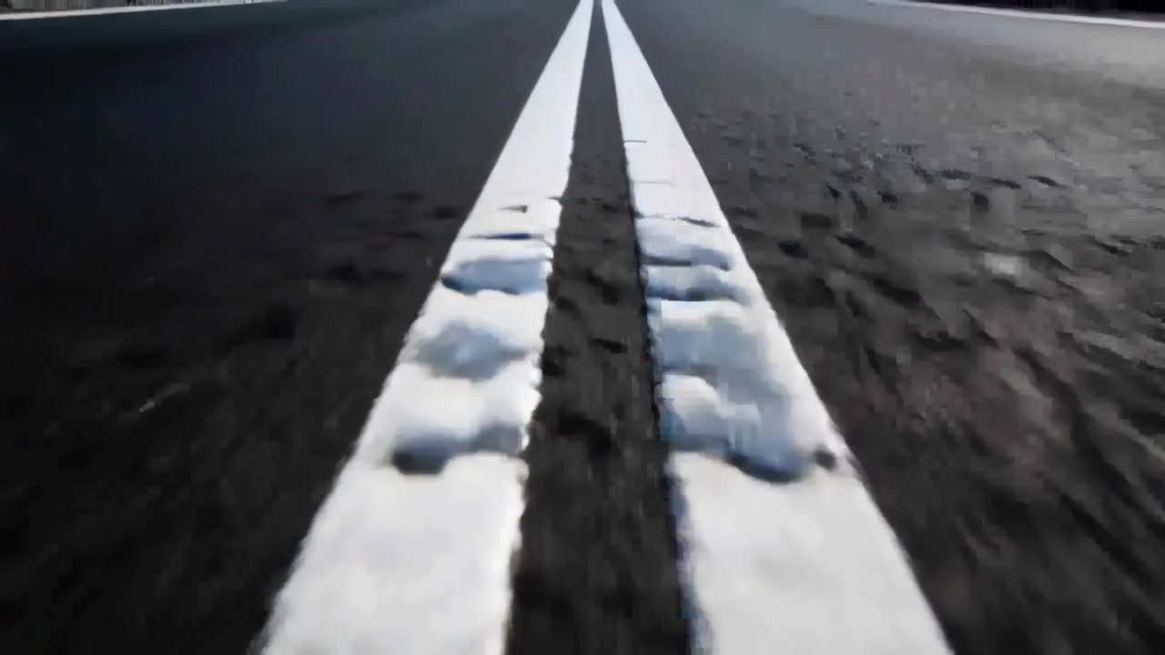 Tracking camera starting close to pavement, moving along double white centerline, revealing texture
