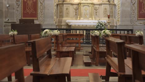 empty church interior with wooden pews, floral decorations, and an ornate altar, ready for a religious ceremony