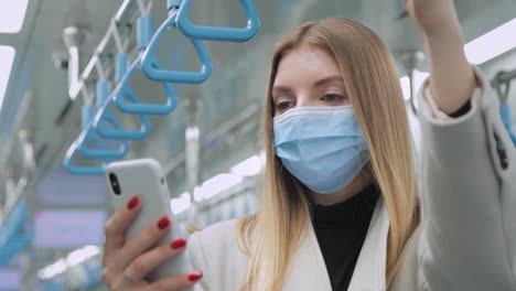 woman using phone on public transportation wearing a mask.