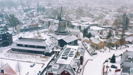 aerial shot of a snowed dutch village with a typical windmill