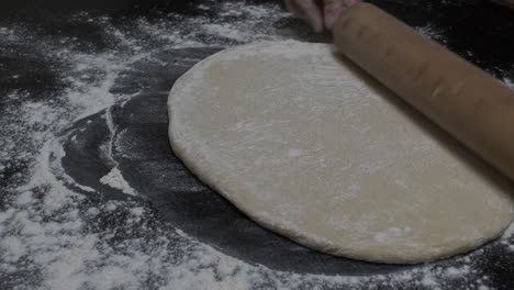 manos femeninas extiende la masa usando la cocina del rodillo