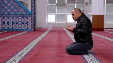 old man wearing mask raising his hands and praying in the mosque