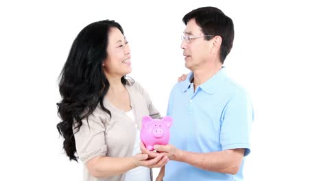 mature asian couple holding a piggy bank