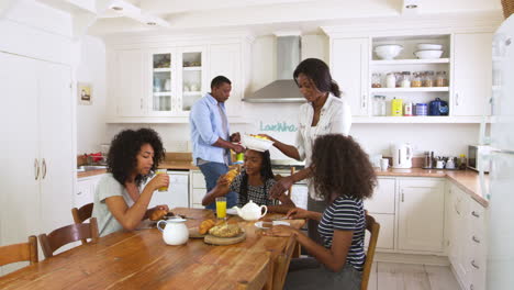 family with teenage children eating breakfast in kitchen