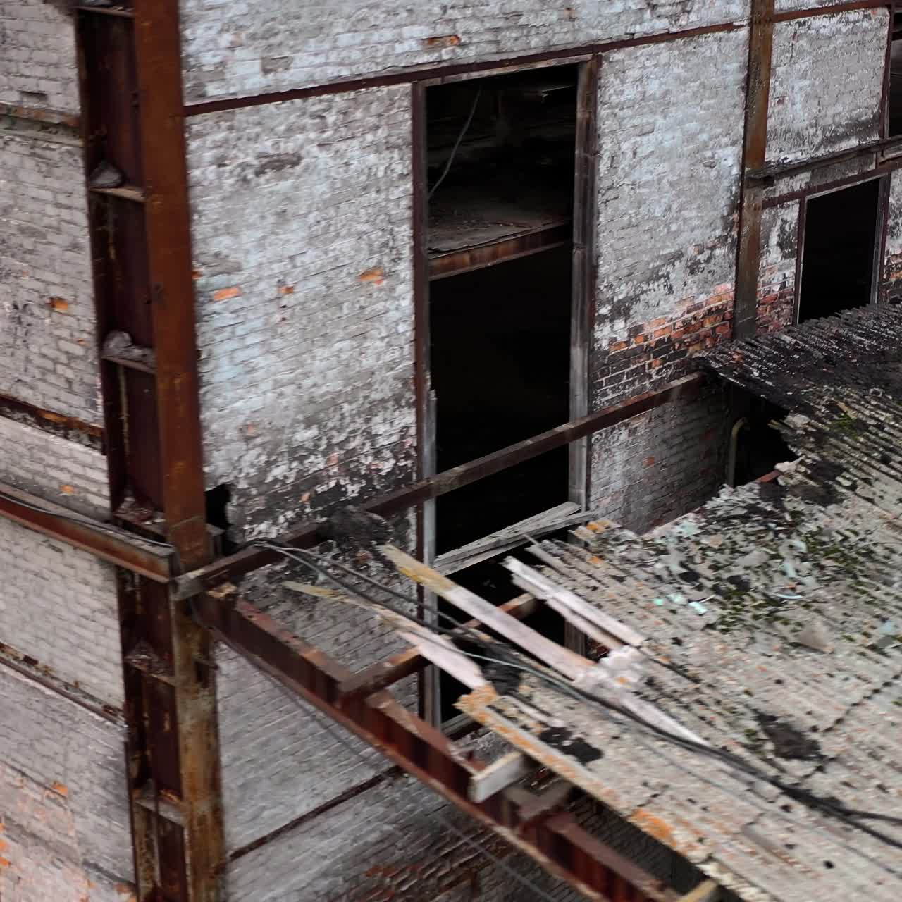 Ruined building. Old architecture with broken windows and many holes in the walls. Exterior of damaged enterprise during military action. Close-up.