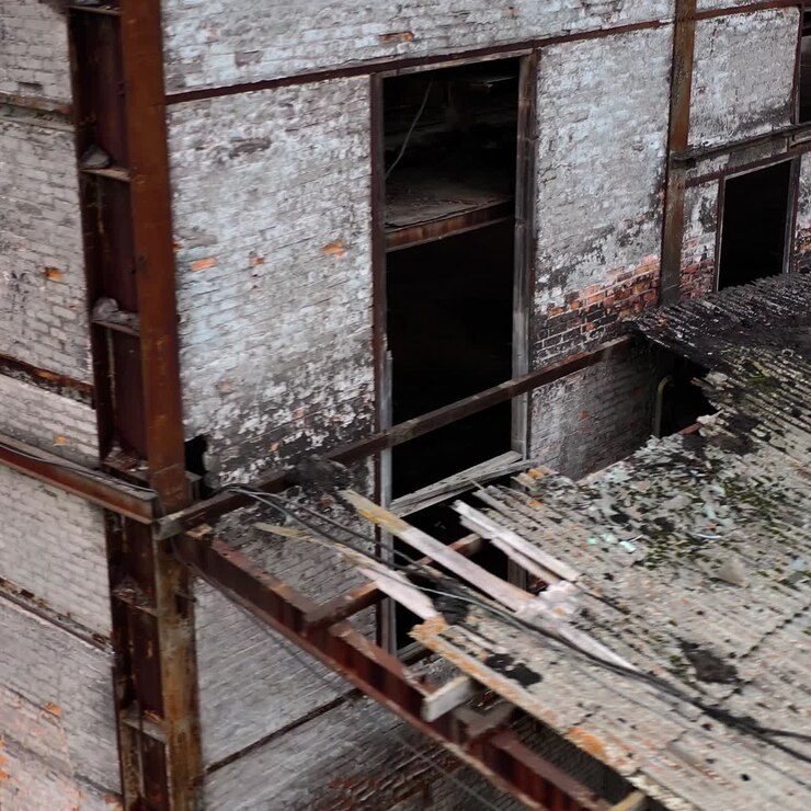 Ruined building. Old architecture with broken windows and many holes in the walls. Exterior of damaged enterprise during military action. Close-up.