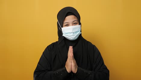 asian muslim woman wearing hijab and mask during coronavirus covid pandemic new normal, woman wearing face protective mask doing greeting gesture