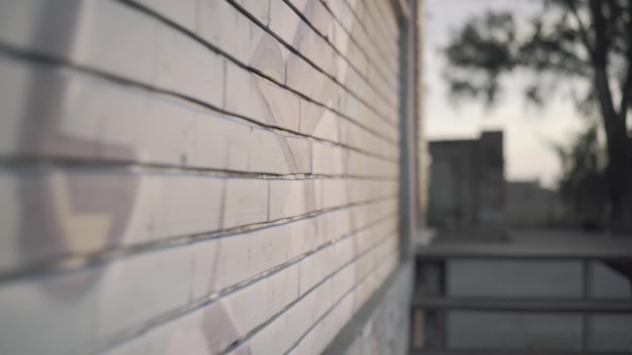 Abandoned warehouse - forward close up along a wall with murals at sunset