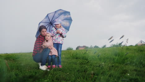 A-woman-with-children-hides-under-an-umbrella-from-the-rain