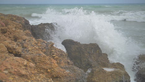 Slow-motion-cinematic-shot-of-a-wave-crashing-on-rocks