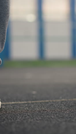 close-up of legs of three athletes in joggers and sneakers walking on court, with blurred background showing another athlete leg also in joggers and sneakers
